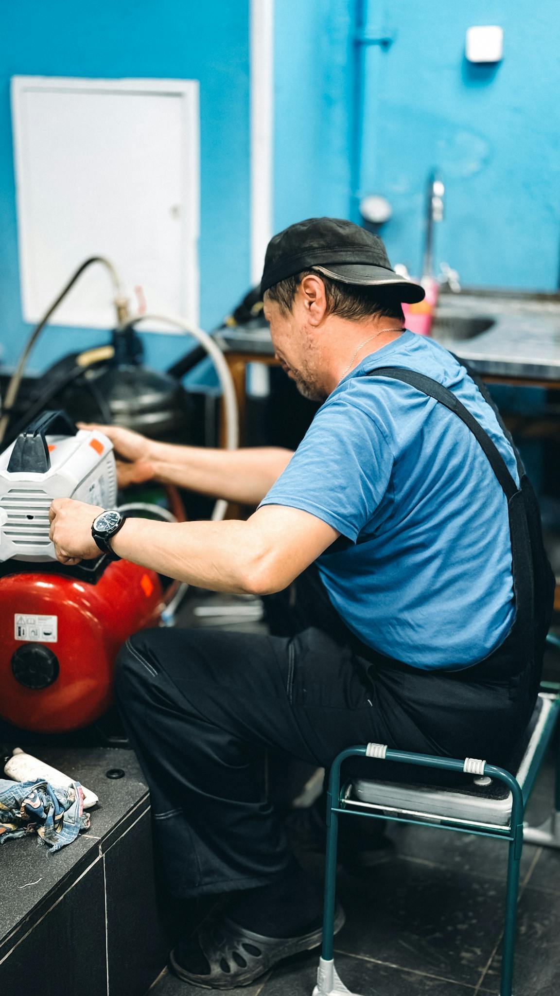 Repairman In Blue Overalls Working Diligently On